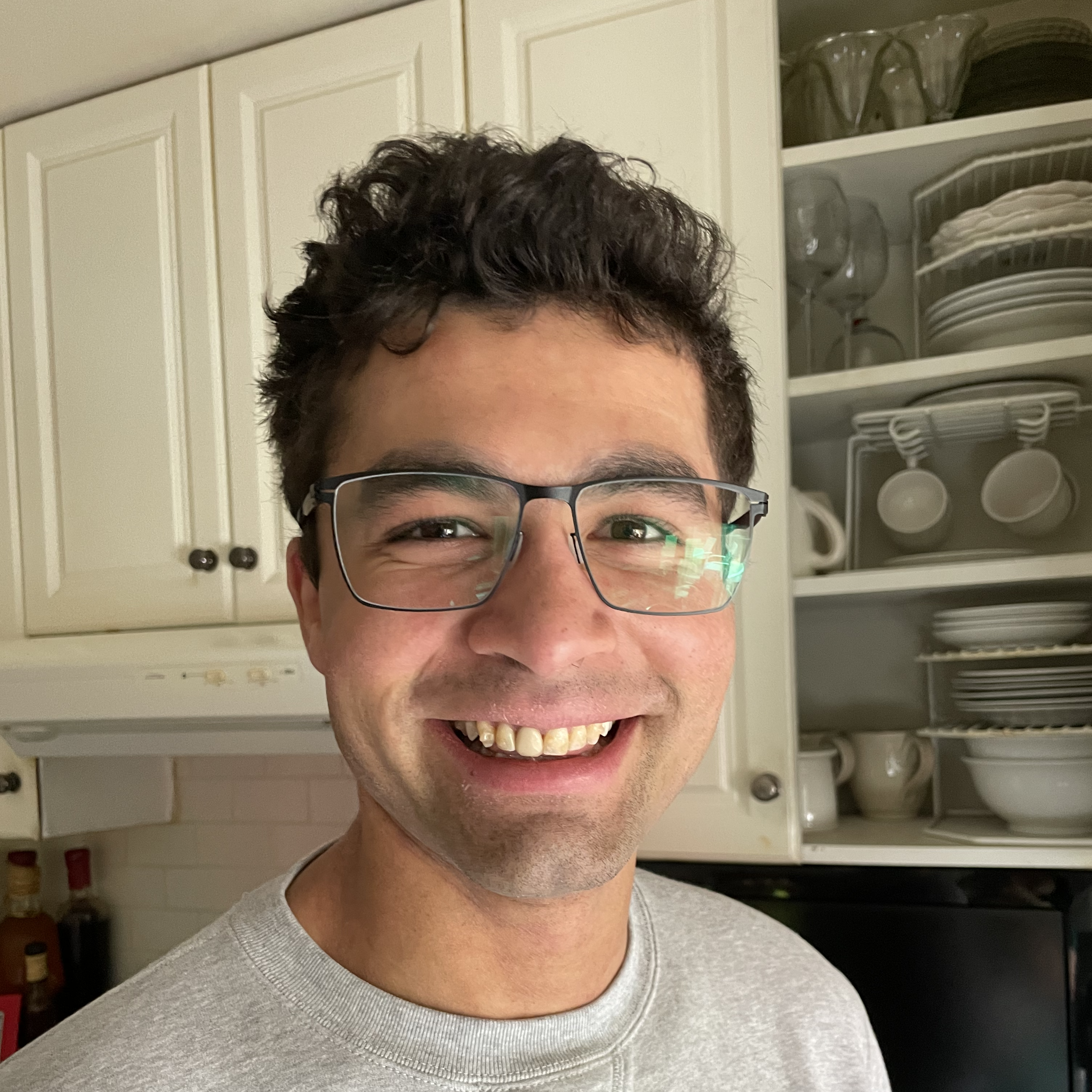 Fernando smiling wearing a gray sweater and black glasses